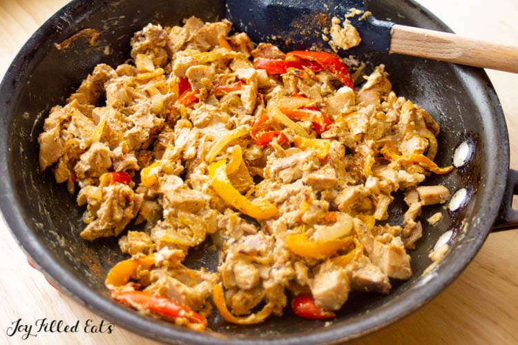 frying pan with chicken peppers and onions in creamy sauce