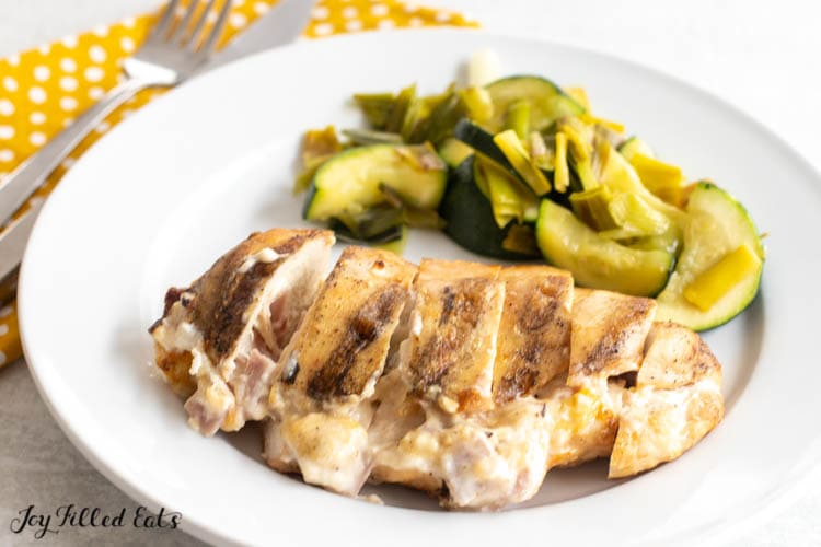sliced stuffed grilled chicken on plate with zucchini and leeks