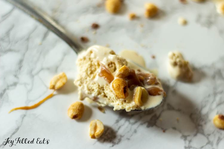 spoon of keto peanut butter ice cream with peanut butter caramel sauce and peanuts
