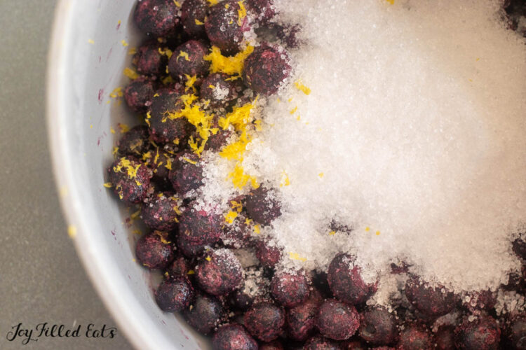 close up of frozen blueberries, sweetener, and lemon zest
