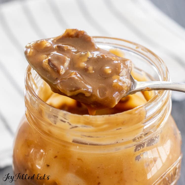 the pecan caramel sauce on a spoon resting on a jar