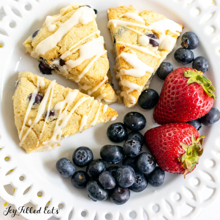 three keto blueberry scones on a plate with fresh berries