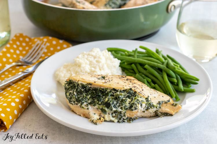 spinach and ricotta stuffed chicken on a plate with green beans and mashed cauliflower
