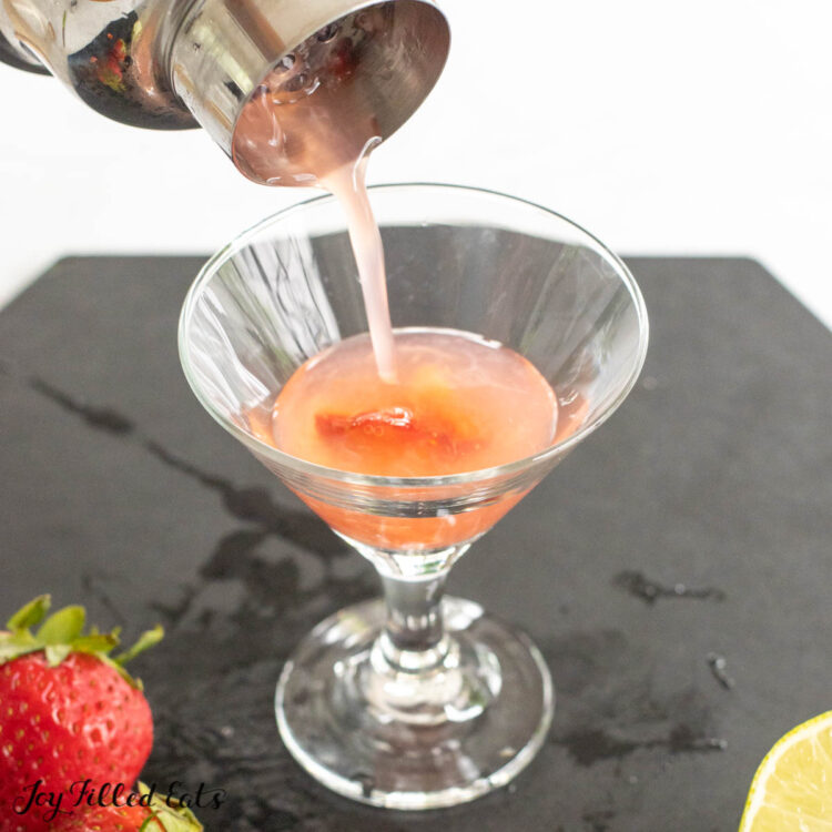 strawberry gimlet being poured into small martini glass