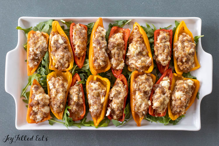 platter of mini Stuffed Peppers with Cream Cheese and Sausage on a bed of arugula