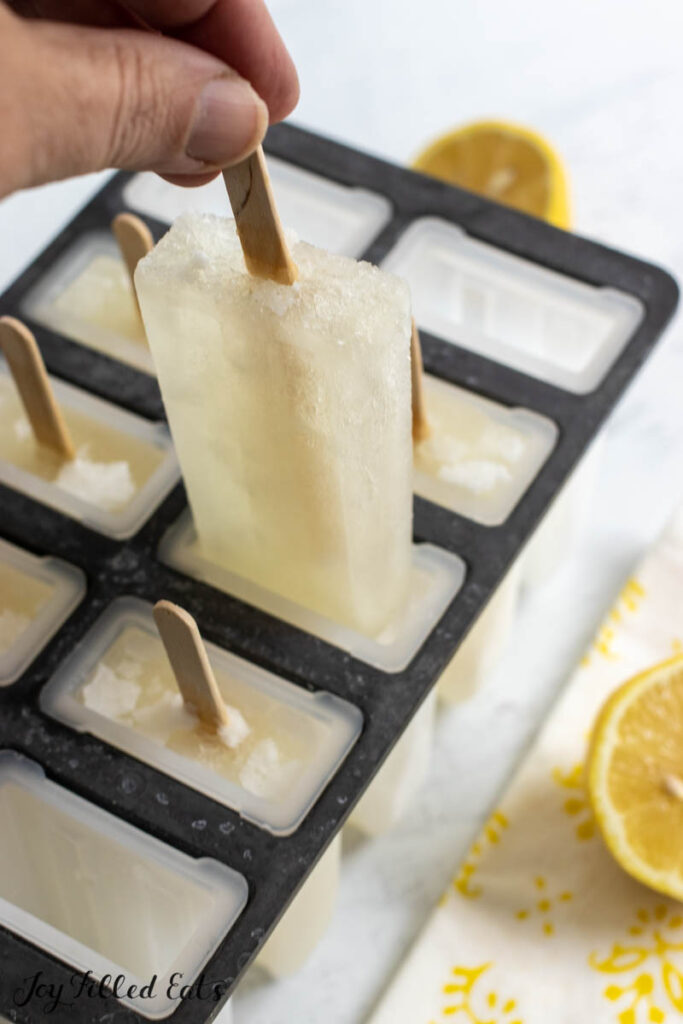hand pulling one of the keto lemonade popsicles out of the mold