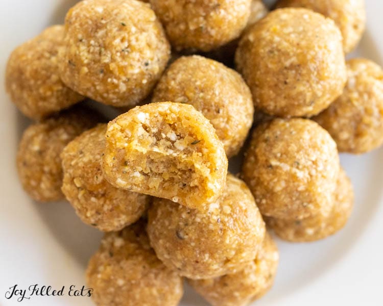 apricot bliss balls with a bite missing on plate close up