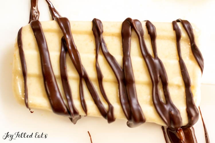 close up of drizzled chocolate on a low carb peanut butter popsicles