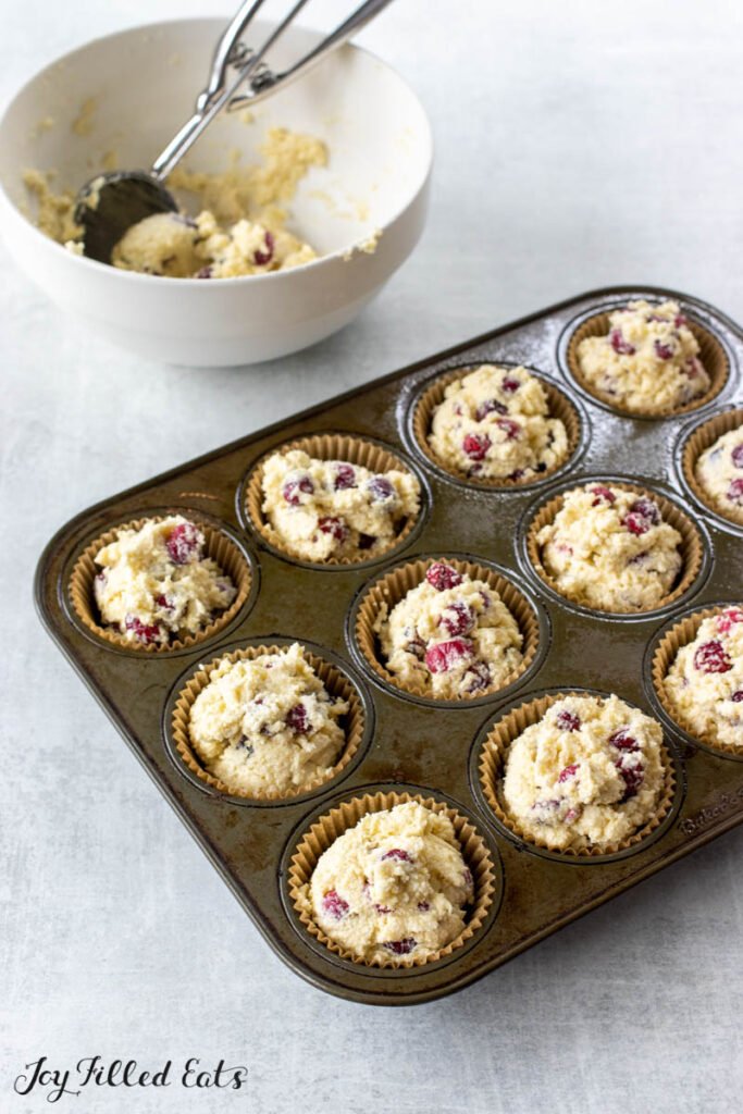 bowl with batter and scoop next to muffin tin