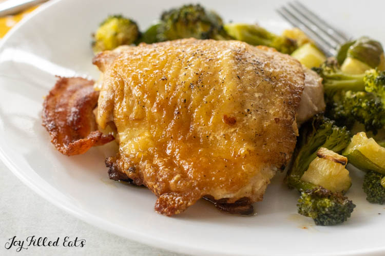 cast iron chicken thighs with bacon on a plate with roasted vegetables