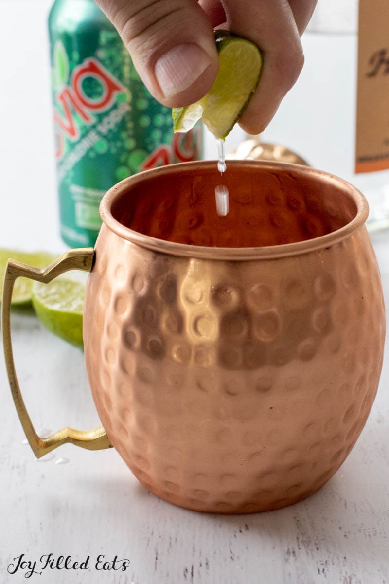 hand squeezing lime into copper mug