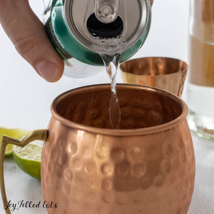 hand pouring diet ginger ale into mug