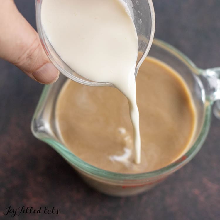 hand pouring cream into coffee