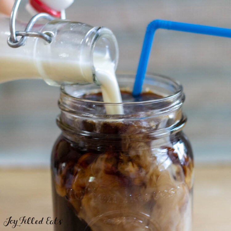 hand pouring the keto coffee creamer recipe into mason jar of iced coffee