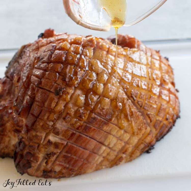 glaze being drizzled over the ham