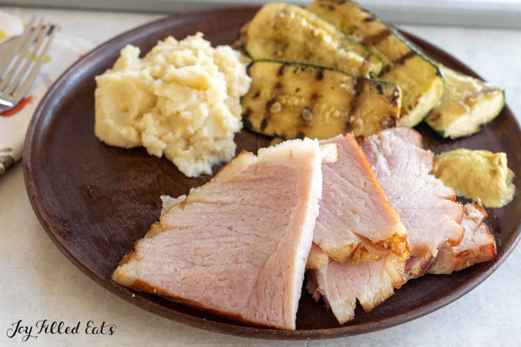 slices of keto glazed ham on a plate with sides