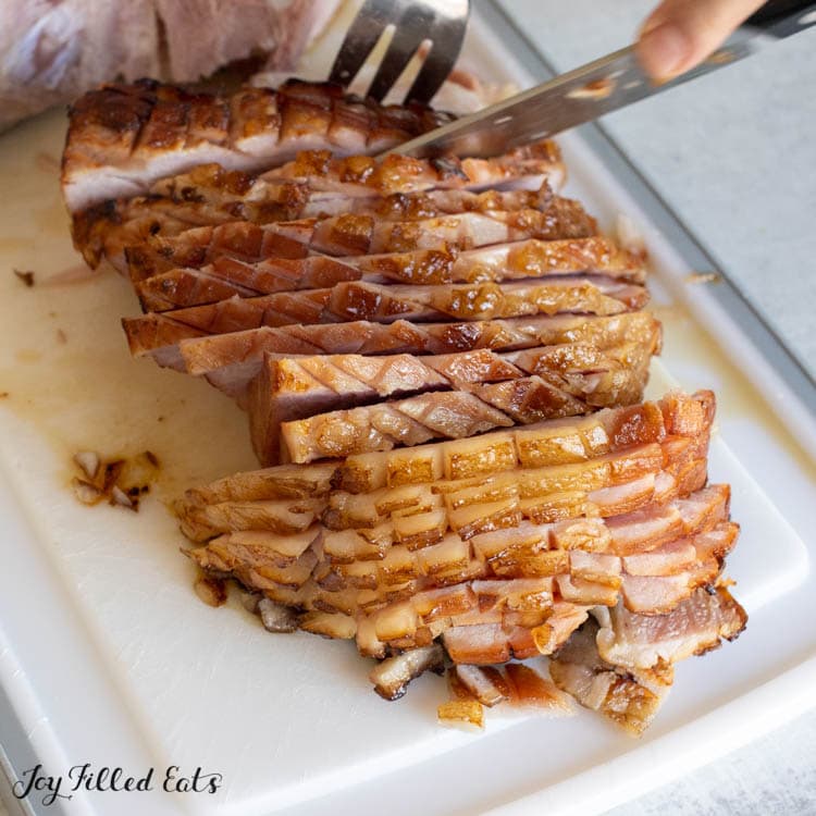 hands holding a fork and knife to slice the pork