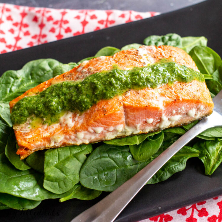close up of the keto salmon recipe with cilantro lime pesto on a bed of spinach