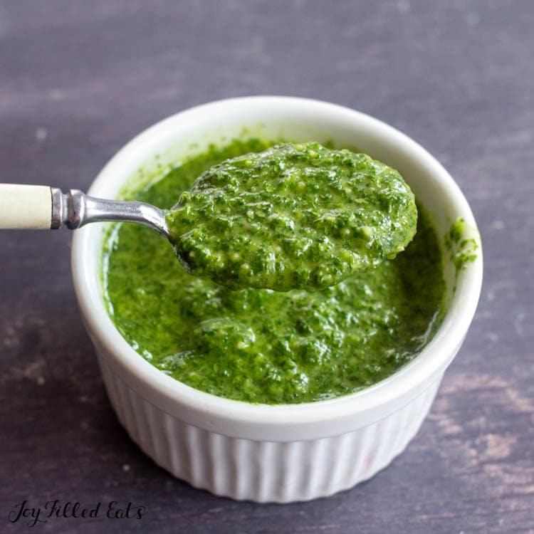 spoon lifting up pesto from small bowl