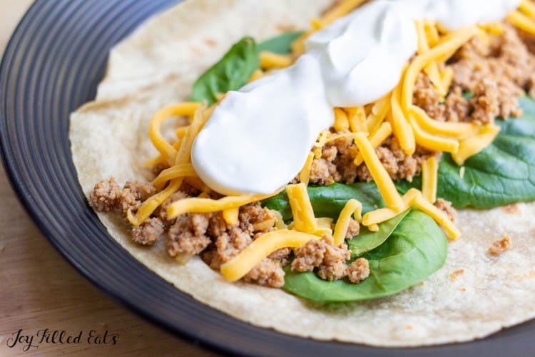 keto tortilla with spinach, meat, cheese, and sour cream