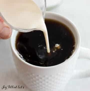 heavy cream being poured into mug of coffee for the keto coffee recipe with heavy cream