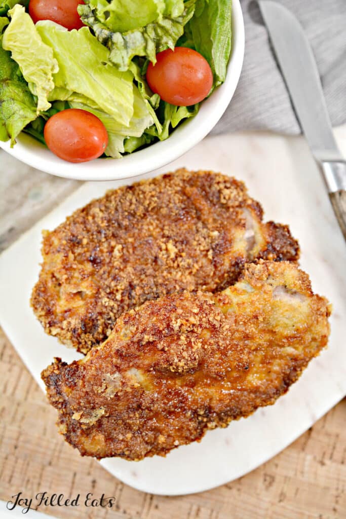 plate with keto air fryer parmesan crusted pork chops next to salad
