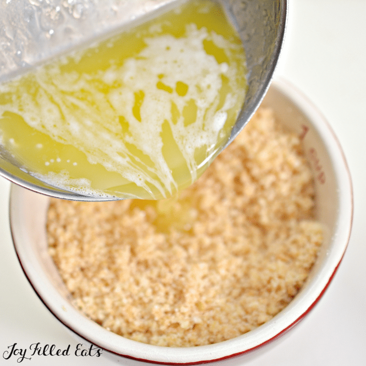 butter being poured into bowl of crumbs
