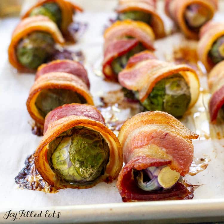 roasted brussels sprouts wrapped in bacon on parchment lined pan