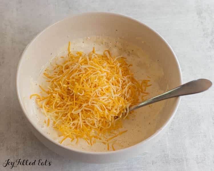 shredded cheese added to bowl of creamy sauce