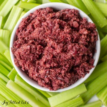 mediterranean olive tapenade close up in a bowl surrounded by a platter of celery sticks