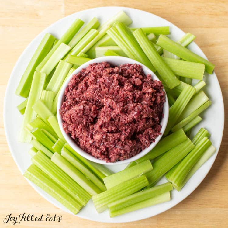 mediterranean olive tapenade in a bowl surrounded by a platter of celery sticks