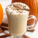 keto pumpkin spice latte recipe shown in a glass mug with cinnamon sticks and pumpkins behind