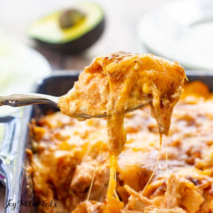 close up of spoon scooping a serving of Mexican Chicken casserole from the dish with cheese strings dripping off spoon