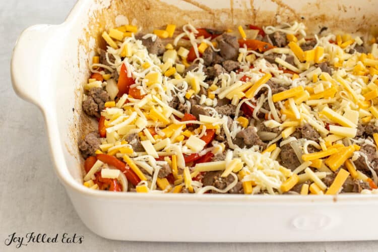 peppers onions sausage and cheese in baking dish