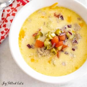 keto cheeseburger soup recipe shown close up with chopped pickles tomatoes and red onions