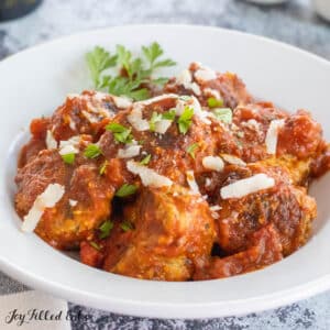 pork sausage meatball recipe shown with marinara sauce and parmesan cheese in bowl
