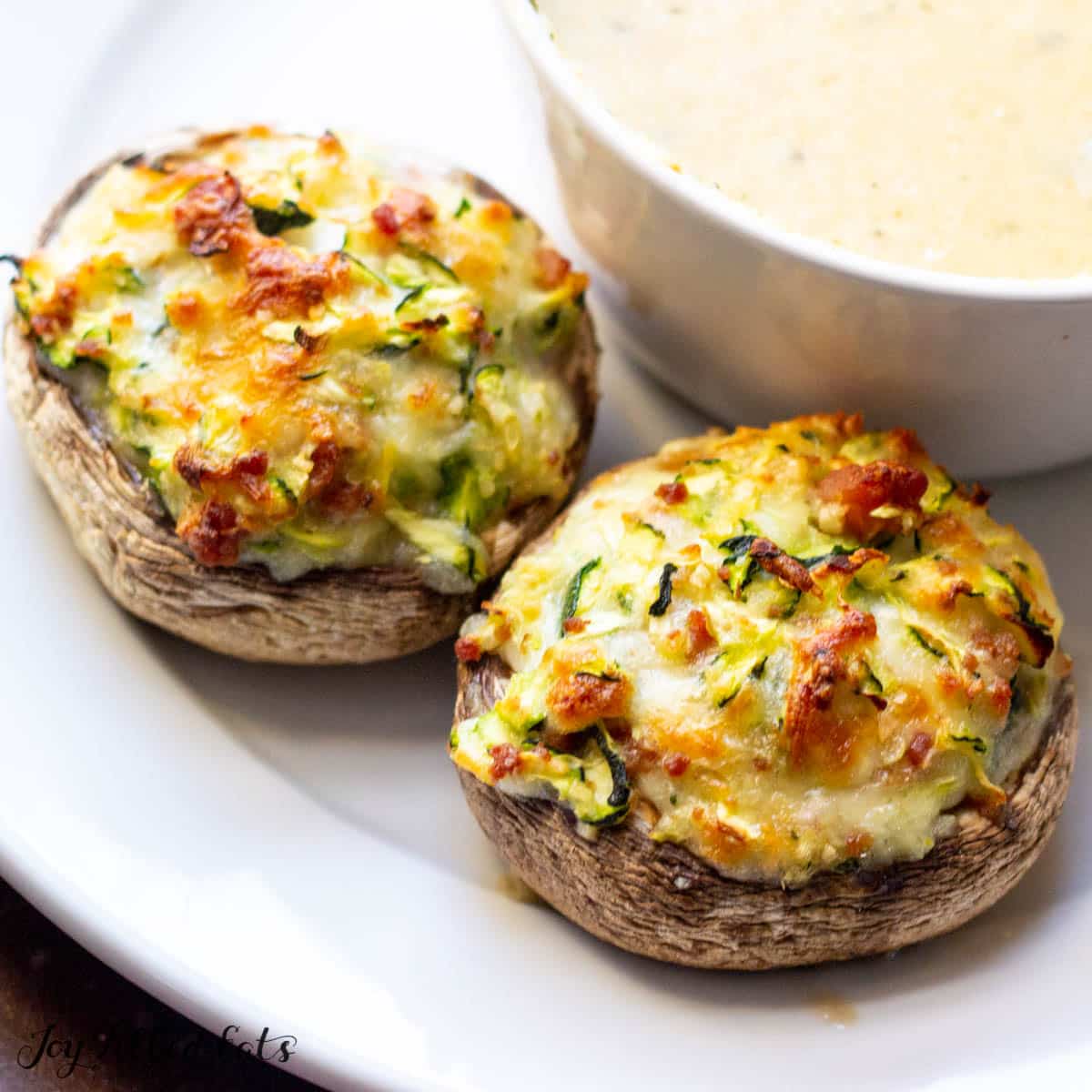 Bacon and Cheese Stuffed Mushrooms served on a plate with a bowl of soup
