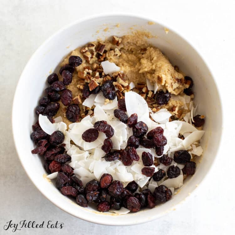 pecans, coconut, and cranberries on top of batter in bowl