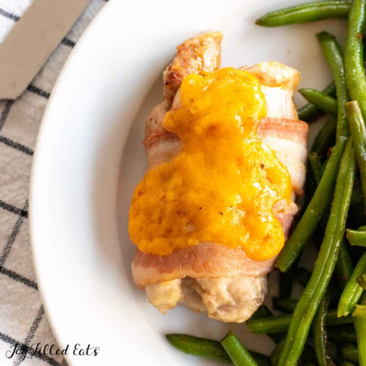 plated bacon wrapped stuffed chicken thigh with green beans