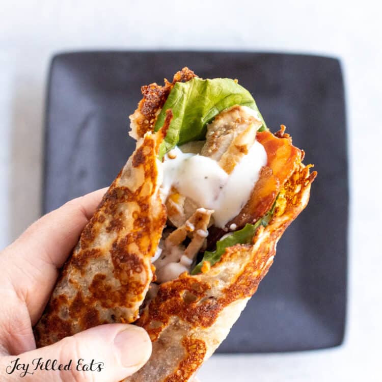 cheese tortilla recipe stuffed with chicken, bacon, and lettuce being held by a hand