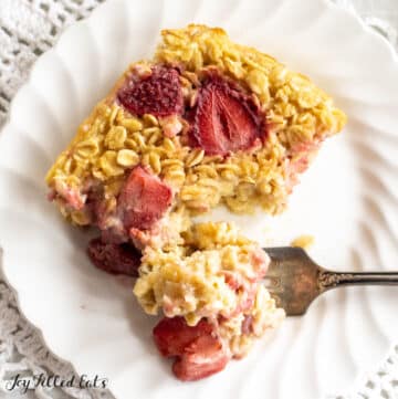 healthy baked oatmeal with strawberries on plate with bite on a fork