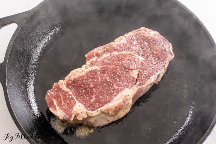 raw steak placed into hot pan