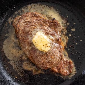 broiled ribeye recipe with garlic herb butter melting on hot steak