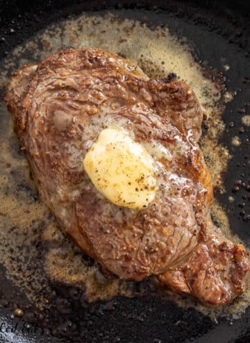 broiled ribeye recipe with garlic herb butter melting on hot steak