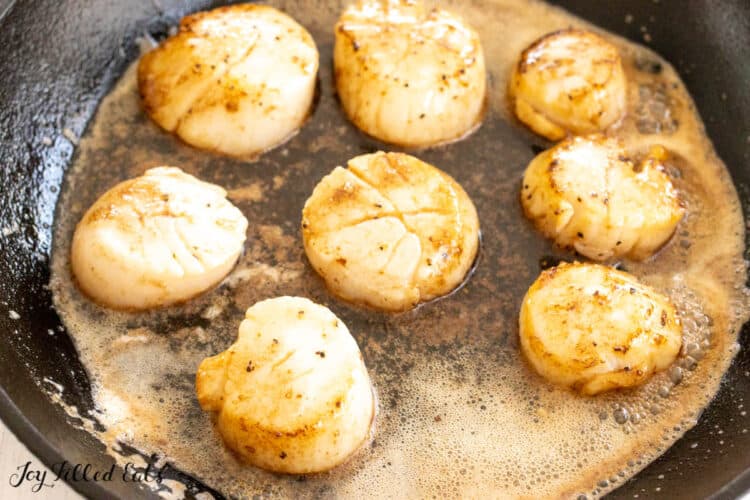 cast iron skillet with scallops in butter