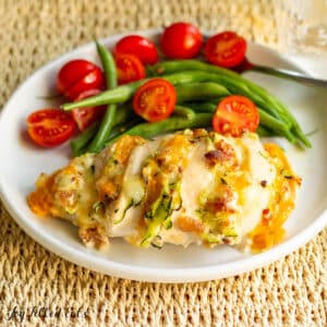 hasselback chicken recipe served on a dinner plate with green beans, and tomatoes