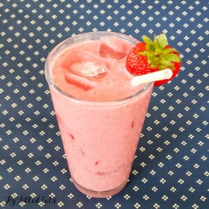 keto pink drink recipe in tall glass with a straw and strawberry