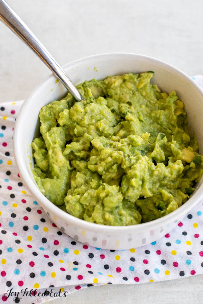 4 ingredient guacamole recipe shown vertical in bowl with spoon