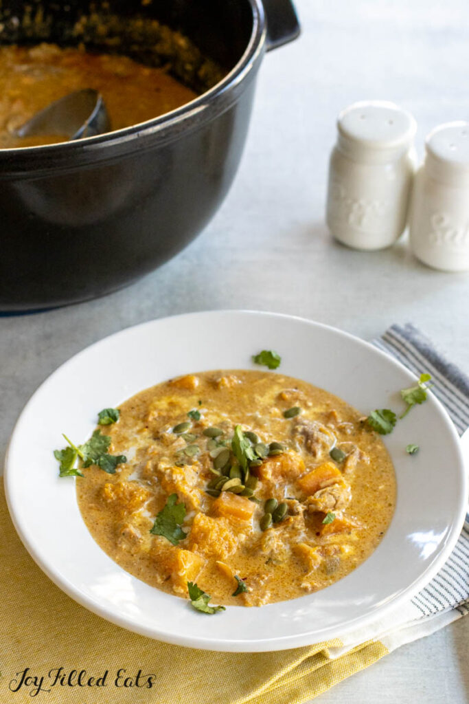 autumn chili with butternut squash in a soup bowl with pot behind