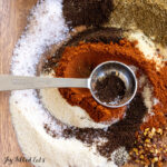 chili seasoning recipe on wood plate with measuring spoon close up
